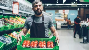 Fim da escala 6x1: funcionário de supermercado segurando uma caixa de tomates